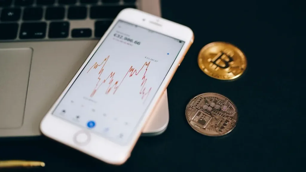 Smartphone showing a trading app next to bitcoin coins