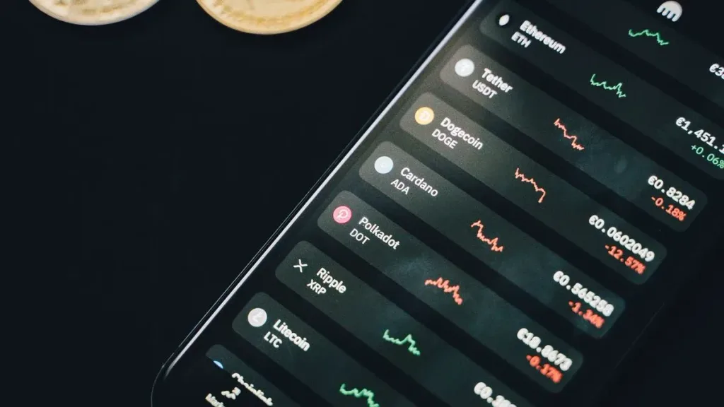 Coins and a smartphone showing financial charts on screen