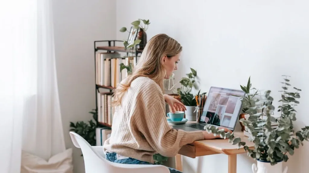 Young woman working from home on a laptop surrounded by plants