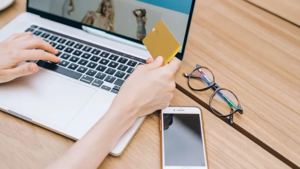 Hand holding a card while making an online payment on a laptop